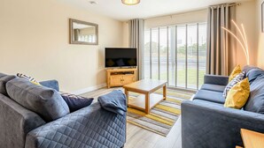 A modern living room with a TV, sofa, and coffee table. - Oystercatcher (Stranraer)