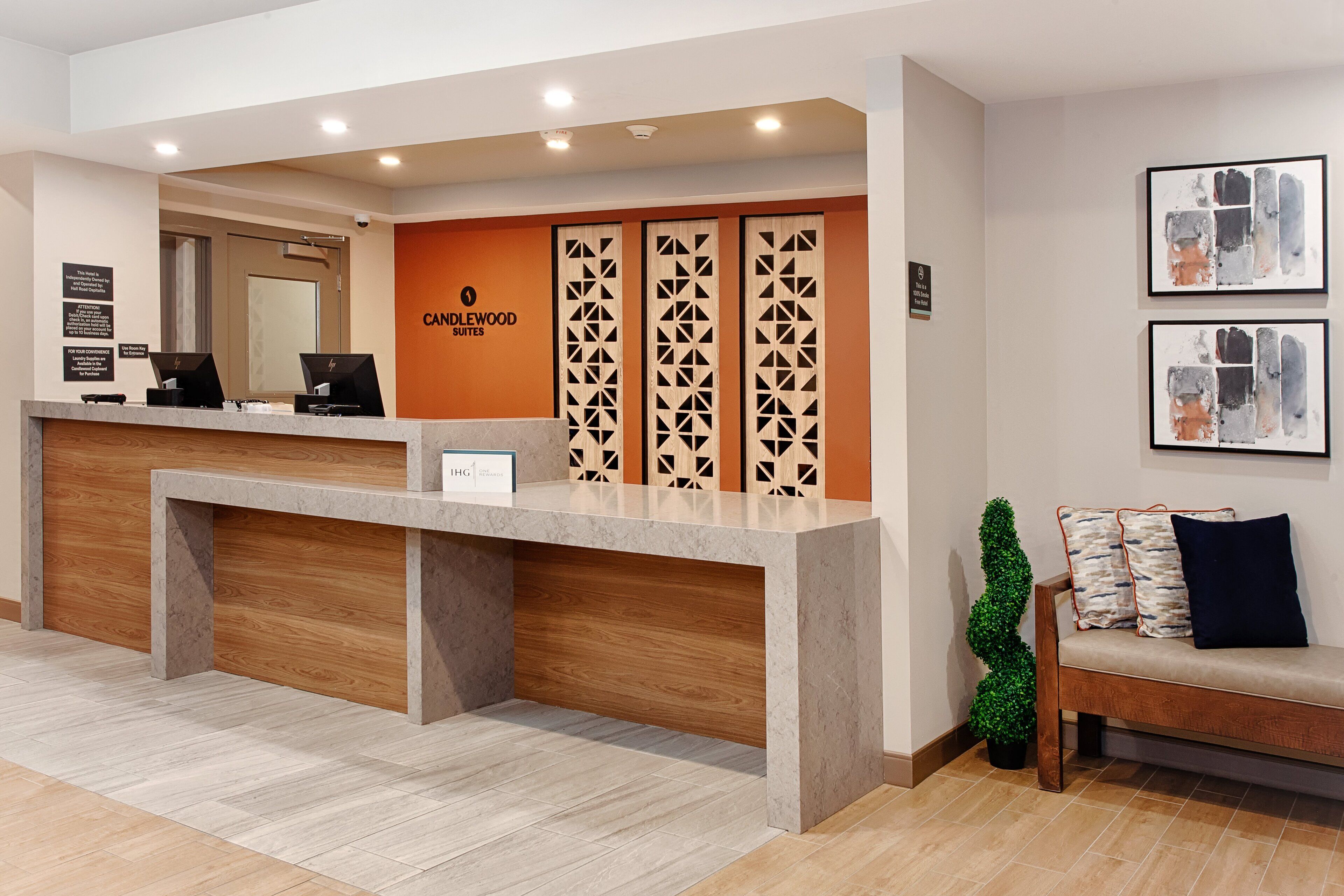 A reception desk with a modern design, a wooden bench, and framed artwork on the wall.
