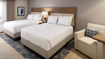 A hotel room with two beds, a sofa, a nightstand, and a lamp.