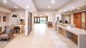 A hotel lobby with a reception desk, seating area, and a view of the outdoors. - Candlewood Suites Detroit Sterling Heights by IHG (Macomb)