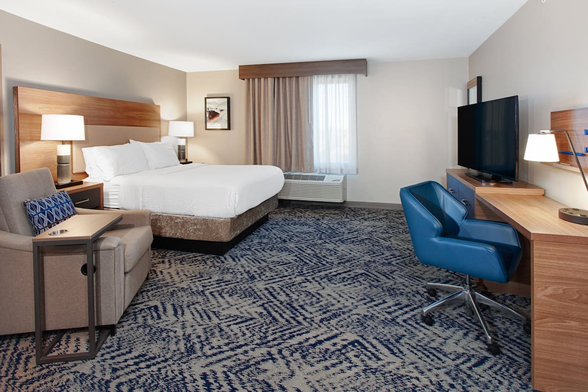 Une chambre d’hôtel équipée d’un lit, d’un bureau, d’une chaise, d’une télévision et d’un appareil de climatisation.