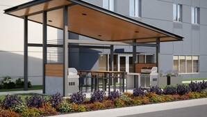A modern outdoor patio with a wooden roof, bar seating, and a grill area. - Candlewood Suites Detroit Sterling Heights by IHG (Macomb)