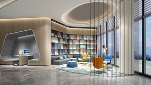 A modern hotel lobby with a curved seating area, a large bookshelf, and a large window offering a city view.