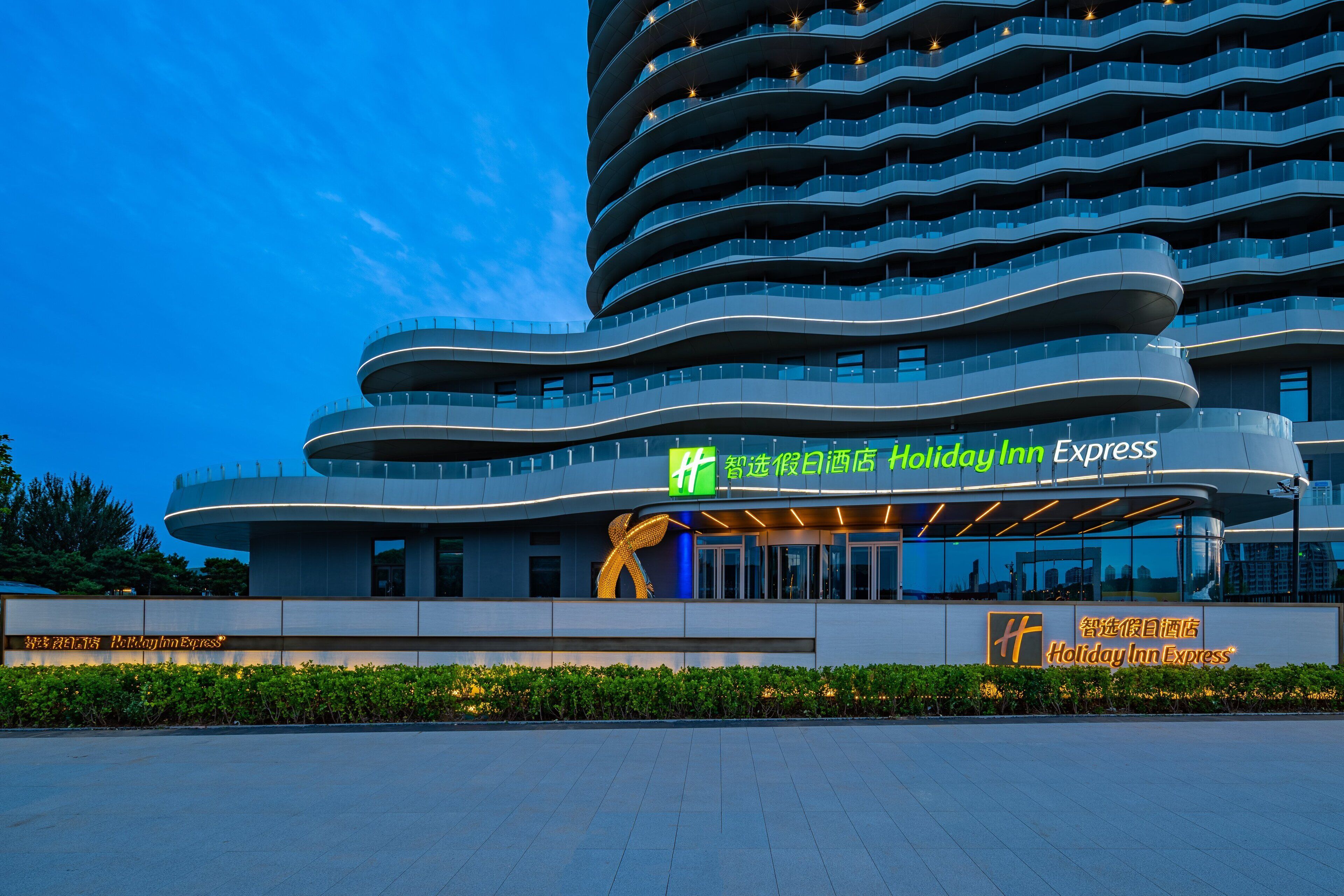 A modern hotel with a curved facade, multiple balconies, and a prominent 'Holiday Inn Express' sign.