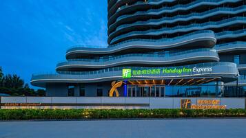 A modern hotel with a curved facade, multiple balconies, and a prominent 'Holiday Inn Express' sign.