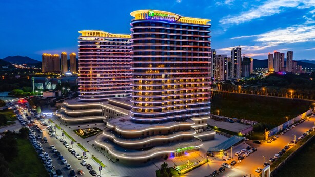 A multi-story hotel with a curved facade, multiple balconies, and a prominent sign at the top.