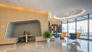 A modern lobby with a seating area, a plant, and a view of the city.