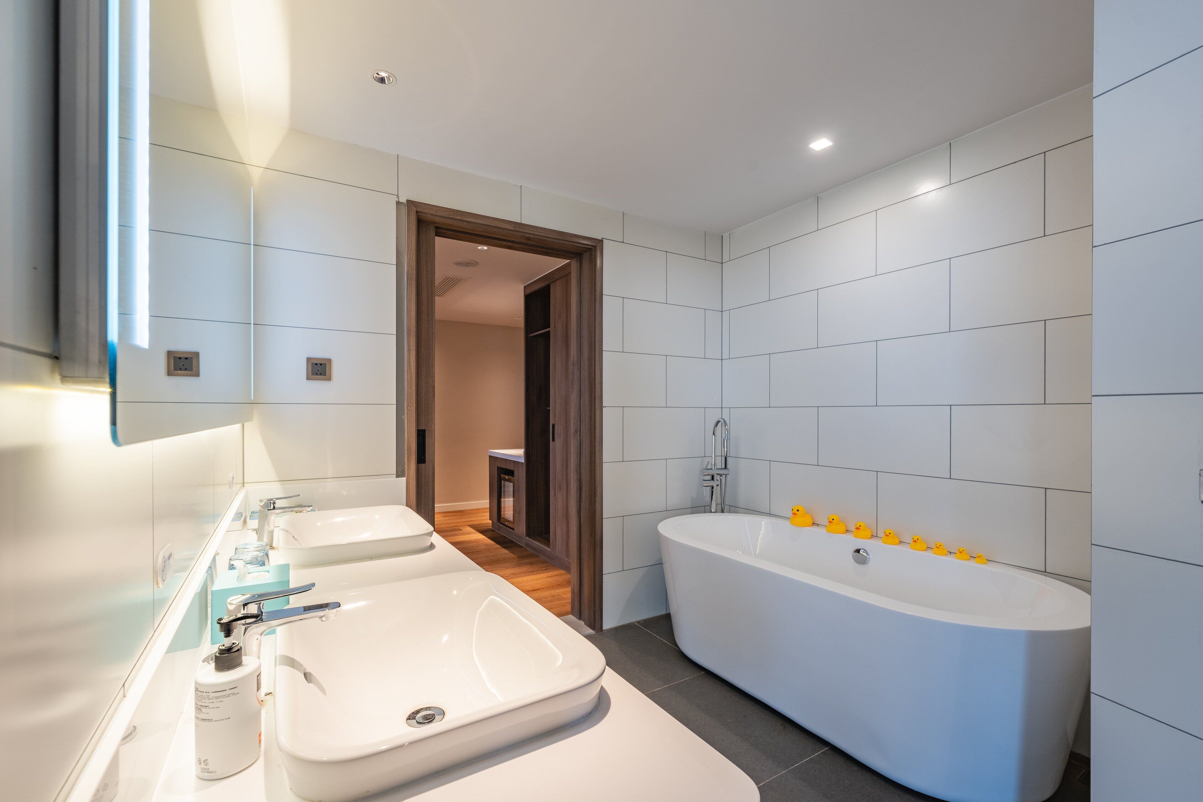 A modern bathroom with a large bathtub, two sinks, and a mirror.