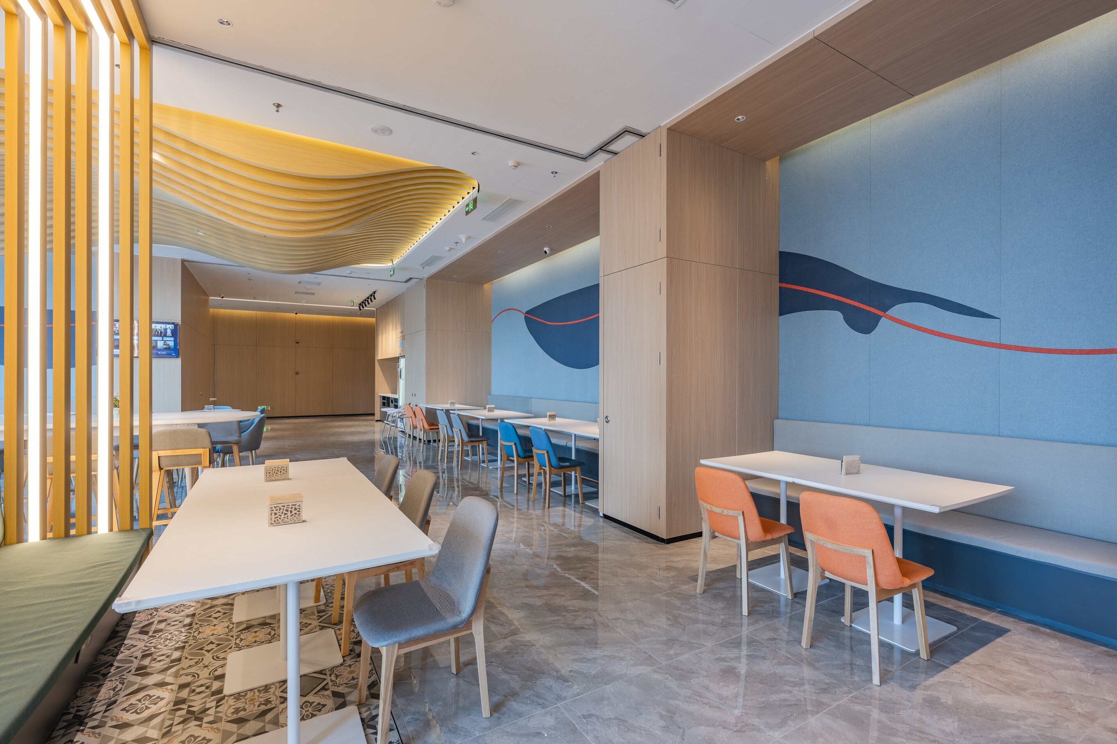 A modern dining area with tables and chairs, a patterned floor, and a large wall mural.