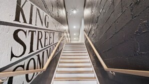 A staircase with a handrail, leading up to a landing with a sign that reads "KING STREET COMMON". - 1/2 Block from King Street, Elegant Old Town Oasis ~ King Bed♛ ~ Free Parking (Alexandria)