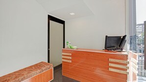 A reception desk with a wooden finish, a black office chair, and a small table with toiletries. - Treebo Villa Inn Aurangabad (Chhatrapati Sambhajinagar)