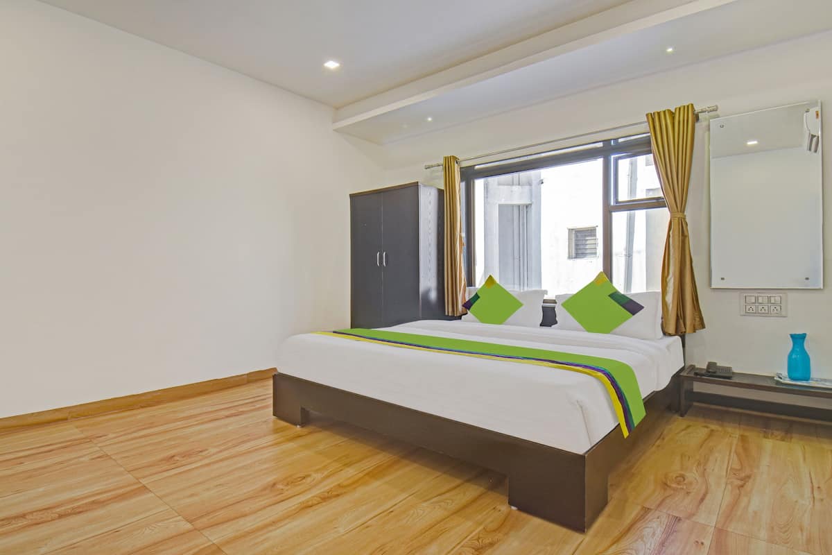 A bedroom with a bed, a wardrobe, a window with curtains, a mirror, and a nightstand.