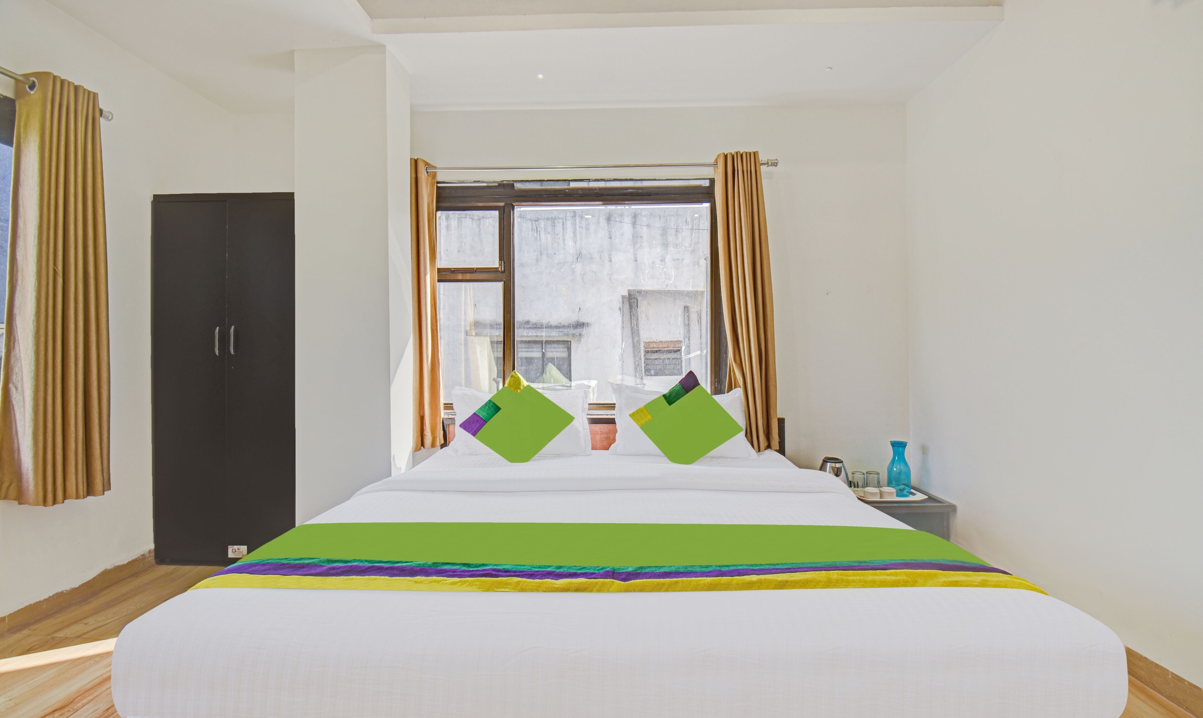 Quarto de hotel com uma cama grande, um guarda-roupa, uma janela com cortinas e vista para o exterior.