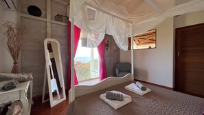 Un dormitorio con cama, espejo, ventana con cortinas, una silla y una puerta de madera.