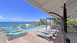 A poolside area with lounge chairs and a view of the ocean. - Villa Tropicale – 5-Bedroom Villa with Pool and Ocean View, Saint-François (Saint-François)