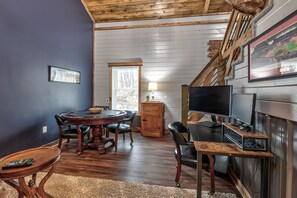 A dining area with a round table, chairs, and a TV on a stand.