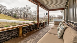 A covered outdoor seating area with stone walls, a wooden bench, and a cushioned sofa.