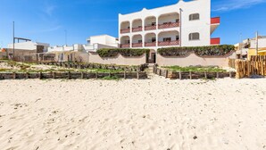 A beachfront hotel with a white facade, multiple balconies, and a sandy beach in the foreground. - Residence Bellavista - App 4 PP (Torre Lapillo)