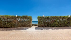 A paved pathway leading to a beach with a clear view of the ocean, flanked by hedges and street lamps. - Residence Bellavista - App 4 PP (Torre Lapillo)