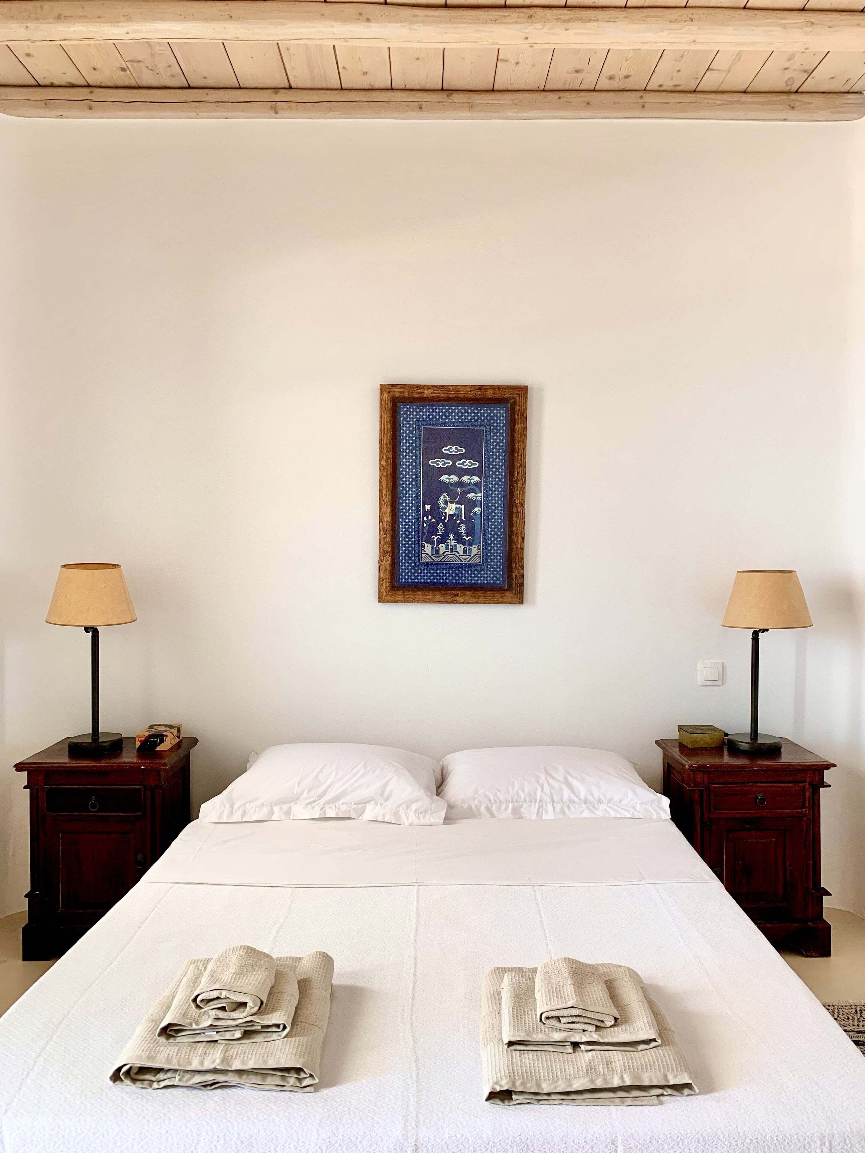 A hotel room with a bed, two nightstands, a framed picture, and two lamps.