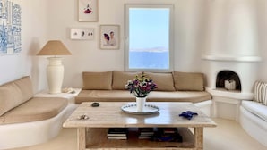 A living room with a beige sofa, a coffee table with a vase of flowers, a lamp, and framed artwork on the wall. - Villa Ramona in Mykonos (Mykonos)