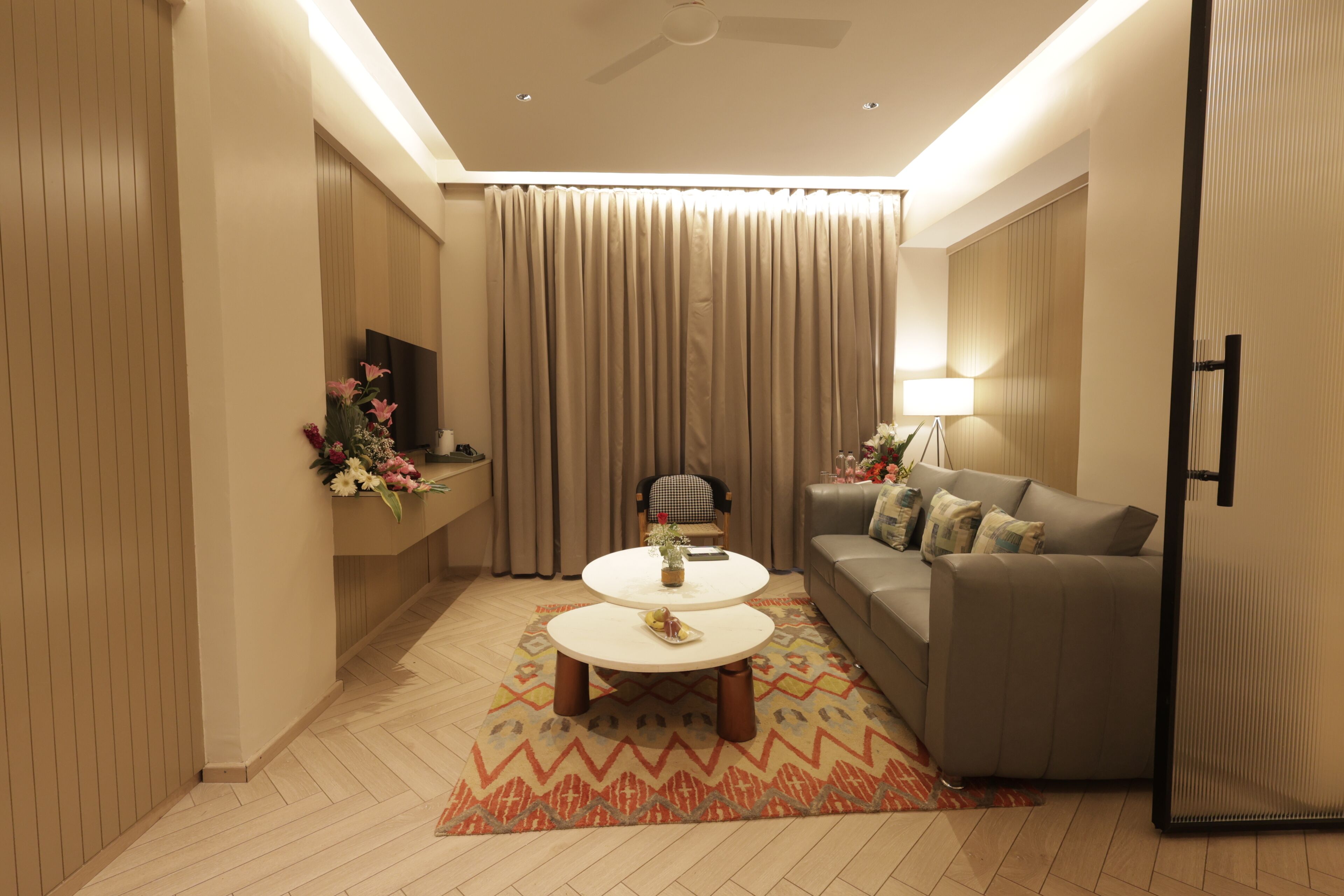 A modern living room with a sofa, a coffee table, a TV, and a decorative vase.