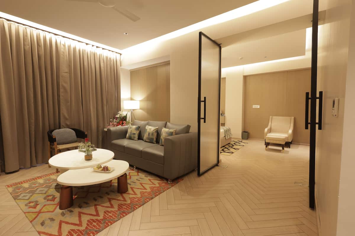 A modern living room with a sofa, two coffee tables, a lamp, and a large mirror.