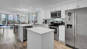 A modern kitchen with white cabinetry, stainless steel appliances, and a central island. - Award-Winning Resort Amenities | Shipwatch 210B (Isle of Palms)