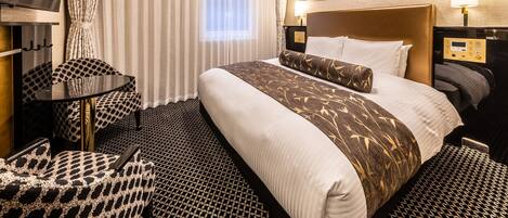 A hotel room with a large bed, a desk, a chair, and a mirror.