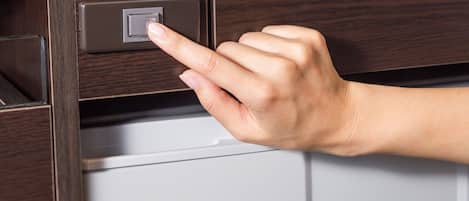 Una mano pulsando un botón en un panel de madera sobre un electrodoméstico blanco.