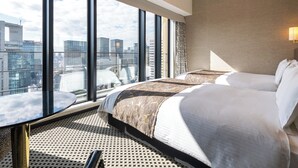 A hotel room with a large window offering a city view, a bed with patterned bedding, and a round table with a remote control. - APA Hotel & Resort Osaka Umeda Eki Tower (Osaka)