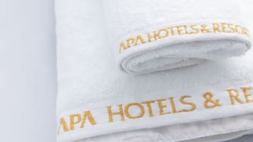 A folded white towel with embroidered text reading "APA HOTELS & RESORT".