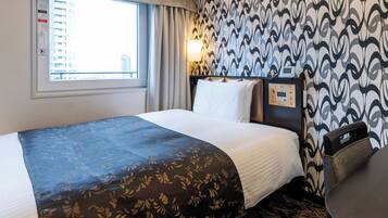 A hotel room with a large bed, a window with curtains, a patterned wall, and a control panel on the wall.
