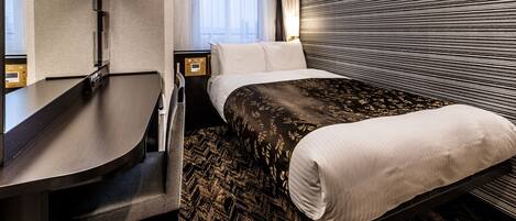 A modern hotel room with a bed, bedside table, and a large mirror.