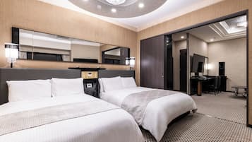 A hotel room with two beds, a desk, a chair, a mirror, and a ceiling light fixture.