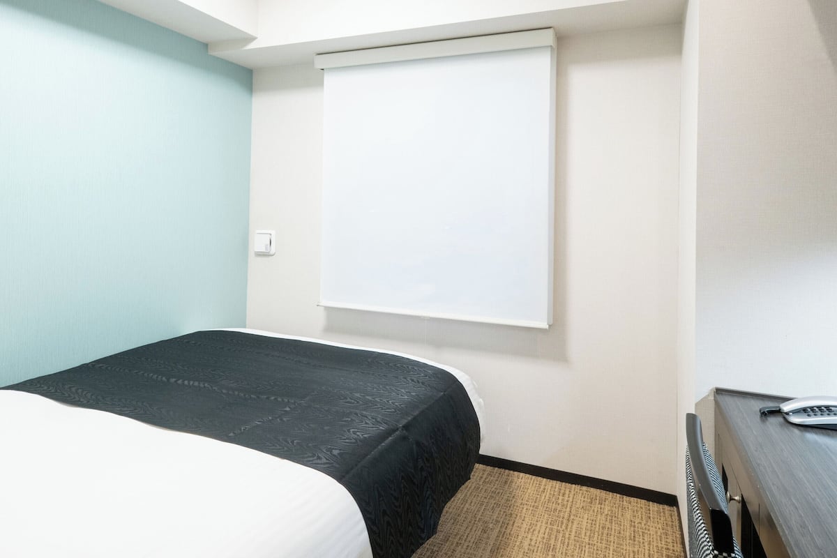 Una habitación de hotel con una cama, un escritorio y una pizarra en la pared.
