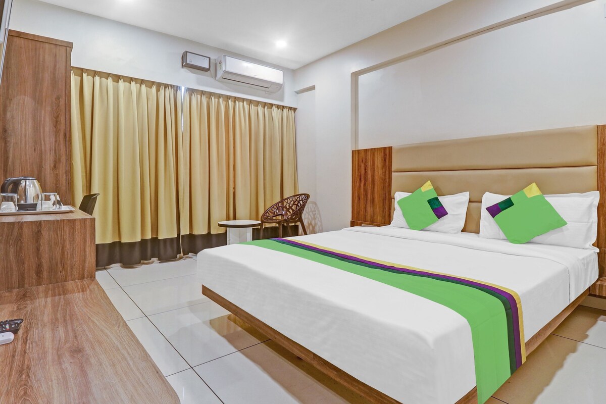 A hotel room with a large bed, wooden headboard, and a small table with a chair.