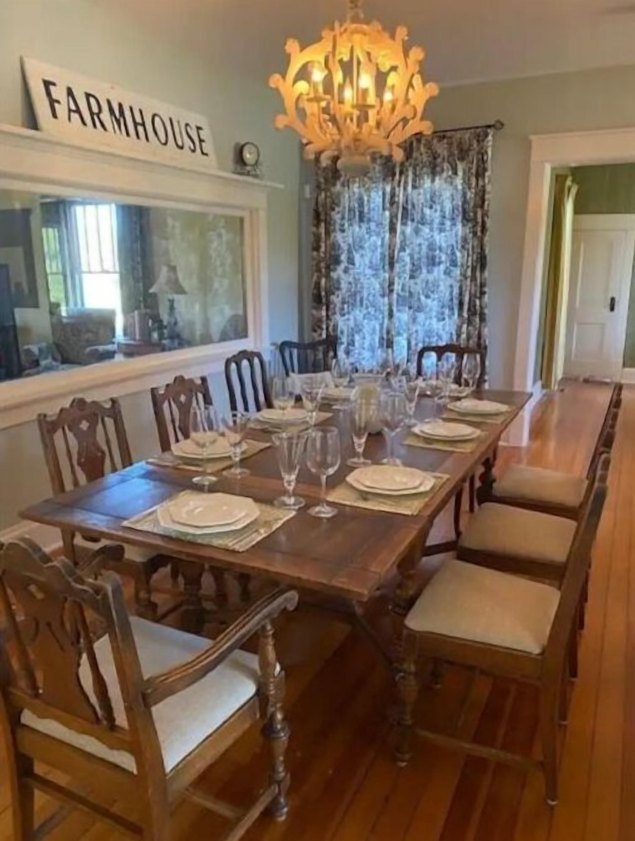 Une salle à manger avec une longue table en bois, dressée pour le repas, entourée de chaises.