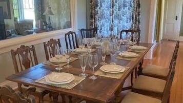A dining room with a long wooden table set for a meal, surrounded by chairs.
