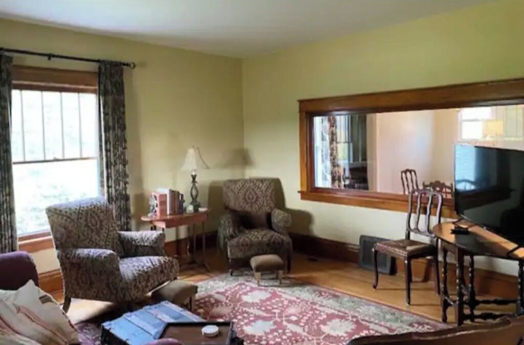 A living room with patterned armchairs, a coffee table, and a television.
