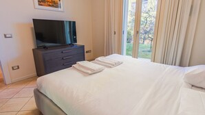 Une chambre d’hôtel avec un lit, un téléviseur posé sur une commode et une vue sur la verdure.