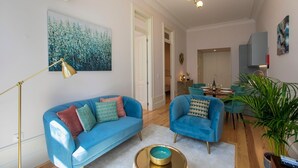 Una sala de estar moderna con un sofá azul, un sillón a juego, una lámpara de pie y un cuadro en la pared.