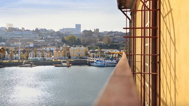 A view of a harbor with boats, a river, and buildings in the background. - Gold Oporto Home River Front - Ribeira (Vila Nova de Gaia)