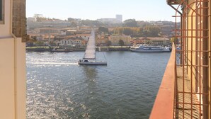 A river with a sailboat and a larger vessel docked. - Gold Oporto Home River Front - Ribeira (Vila Nova de Gaia)