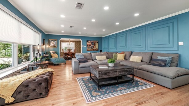 A spacious living room with a grey sectional sofa, a dark coffee table, and a patterned rug. - Spacious Midcentury home located 1 block from Oaklawn Racing and Gaming (Hot Springs)