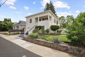 A two-story house with a front porch, a stone retaining wall, and a well-maintained lawn.