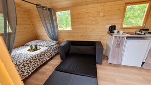 Ein gemütlicher Raum mit Bett, Schlafsofa, einer kleinen Küchenzeile und einem Fenster.