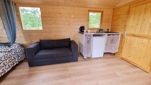Ein kleines Zimmer mit Küchenzeile, einer Couch und einem Bett.