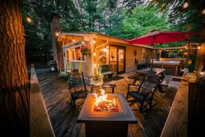 A wooden deck with a fire pit, outdoor seating, and a covered area with string lights. - Catskill Chalet: Hunter Mtn Ski Chalet w/Spa (Tannersville)