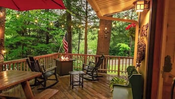 Enjoy dining or socializing on the deck, surrounded by lush greenery and a fire feature.